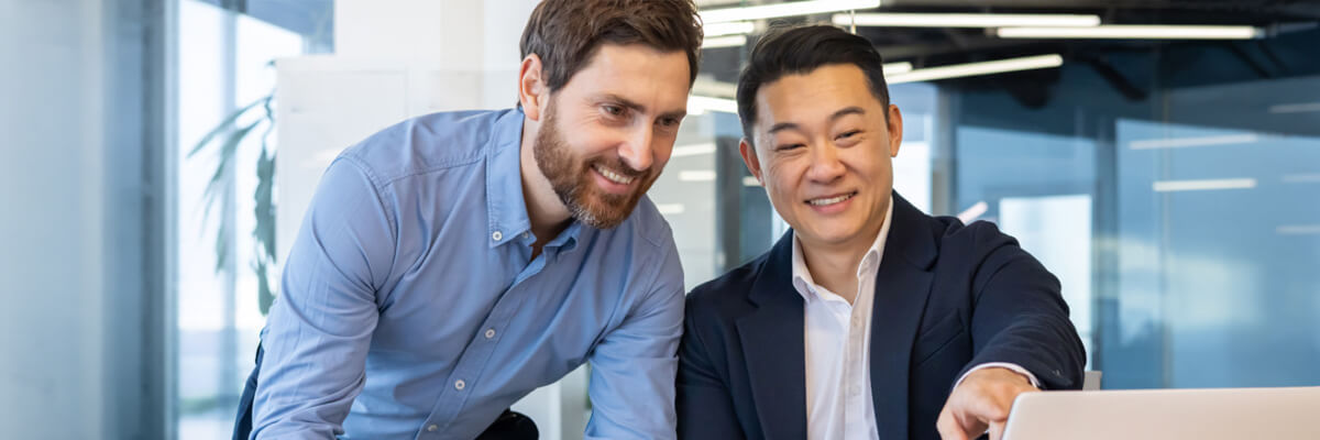 Two business professionals review an AI agent cheat sheet together on a laptop during a collaborative work session.