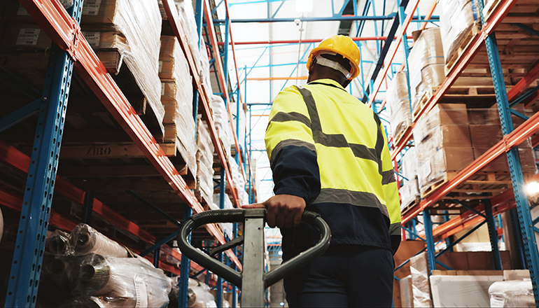 Warehouse, man and worker pull pallet truck for supply chain, restock inventory or moving storage freight. Factory, engineer and trolley for cargo, distribution logistics or back in shipping industry.