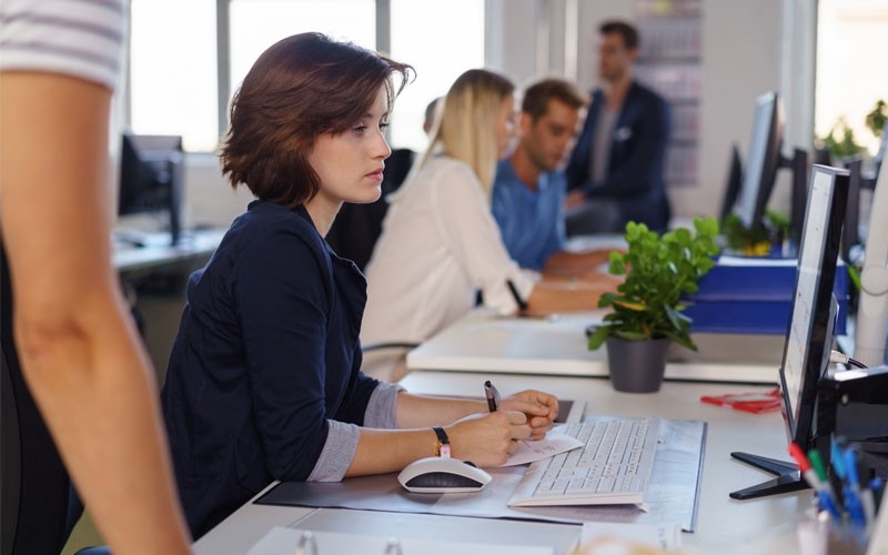 Woman working at benching desk in open office 