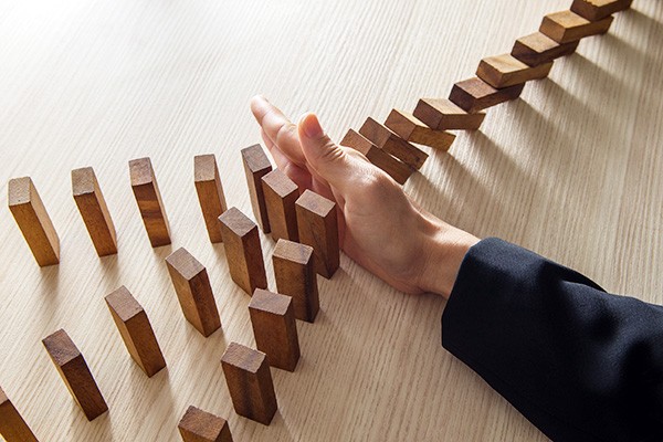 Hand stopping dominoes falling