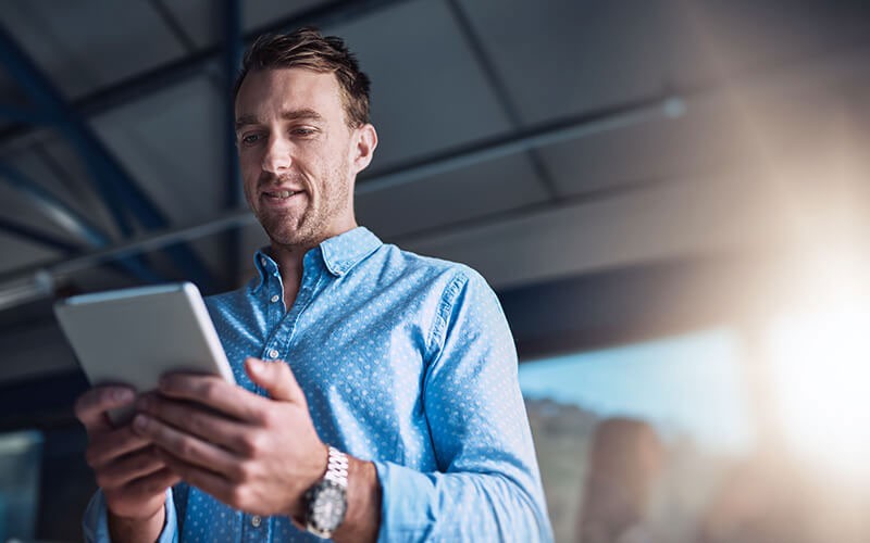Businessman checks his teams projects off tablet computer between offices