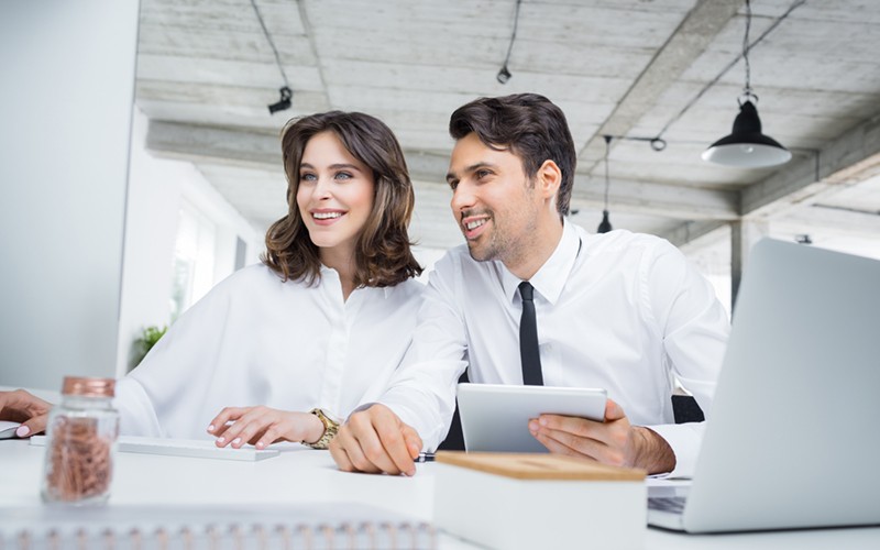Business professionals with devices review workload assessment on computer
