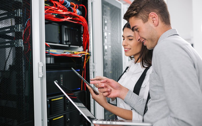 Two IT engineers on-site in data center with laptop