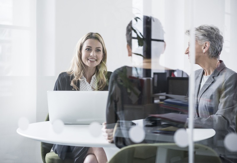Female colleagues behind glass meet in office