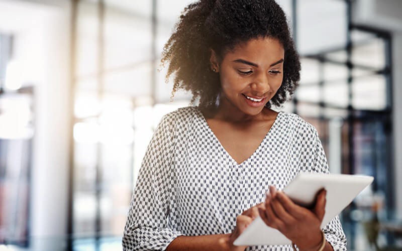 Smiling woman on tablet device in bright open office