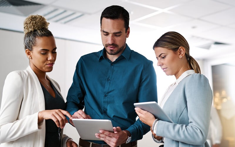 Business colleagues gathered around in hallways with tablets