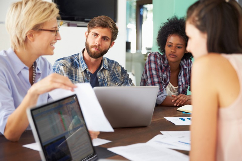 Group of young business people talking at table.